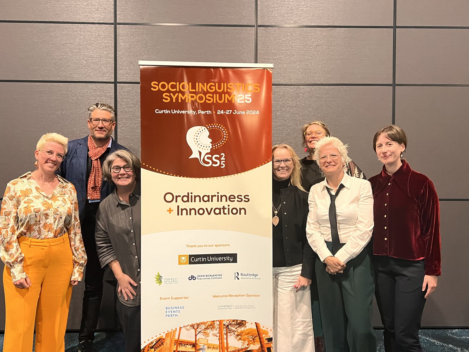 Jody with colleagues beside a Sociolinguistics Symposium banner